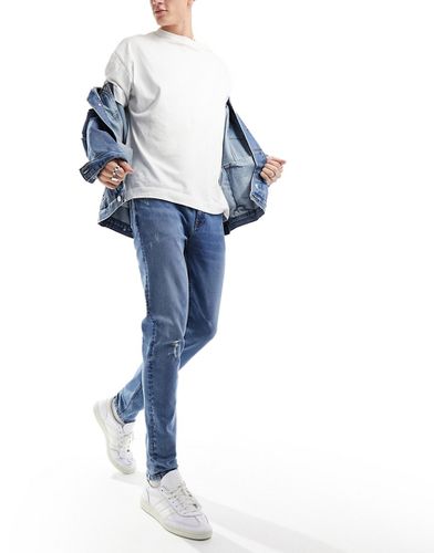 Jeans skinny lavaggio scuro con strappi sulle ginocchia - ASOS DESIGN - Modalova