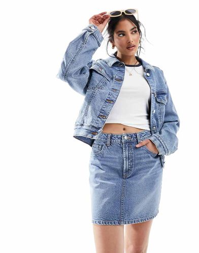 Minigonna a vita alta in denim lavaggio medio - ASOS DESIGN - Modalova