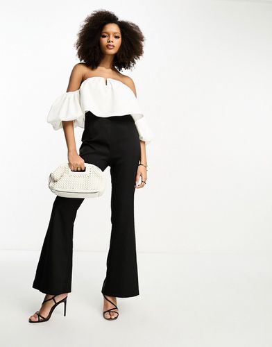 Tuta jumpsuit con maniche a sbuffo e scollo Bardot con pantaloni a zampa bianca e nera - In The Style - Modalova
