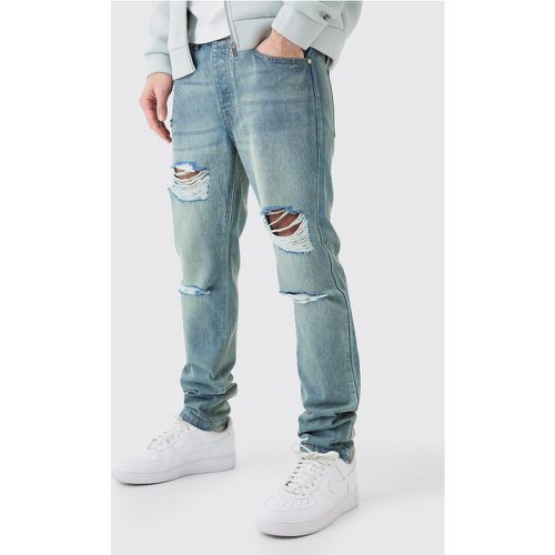 Jeans Slim Fit in denim rigido blu antico con strappi all over - boohoo - Modalova